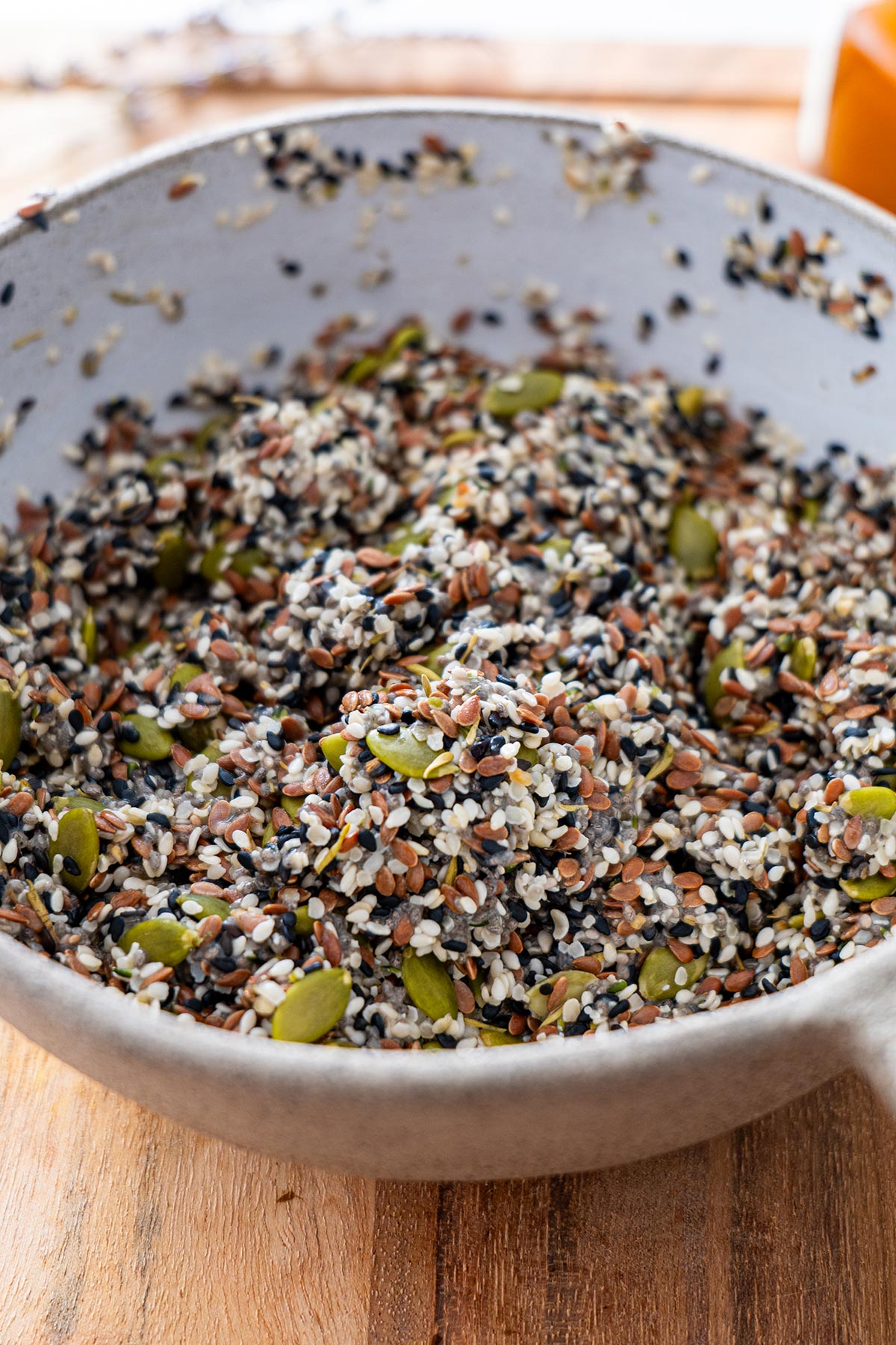Detailed close-up of the seed mixture in a grey mixing bowl on a wooden surface.