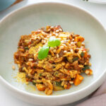 Close-up of a serving of vegan one-pot orzo Bolognese topped with pine nuts and nutritional yeast.