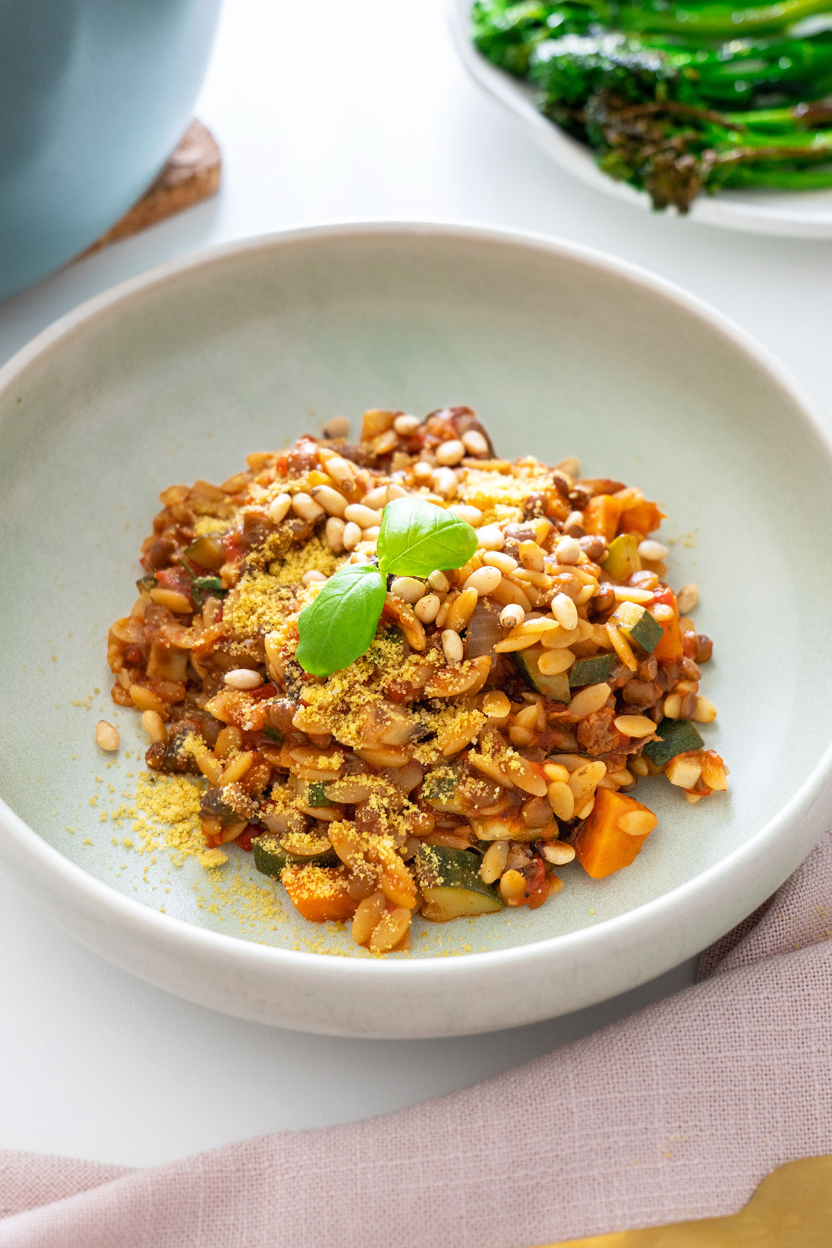 Close-up of a serving of vegan one-pot orzo Bolognese topped with pine nuts and nutritional yeast.