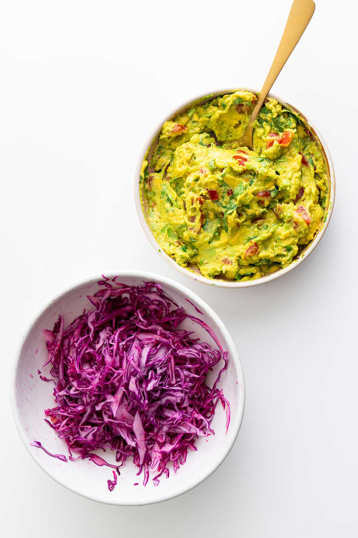 Guacamole and red cabbage slaw for vegan sheet pan fajitas neatly arranged, showcasing the variety of textures and colors.