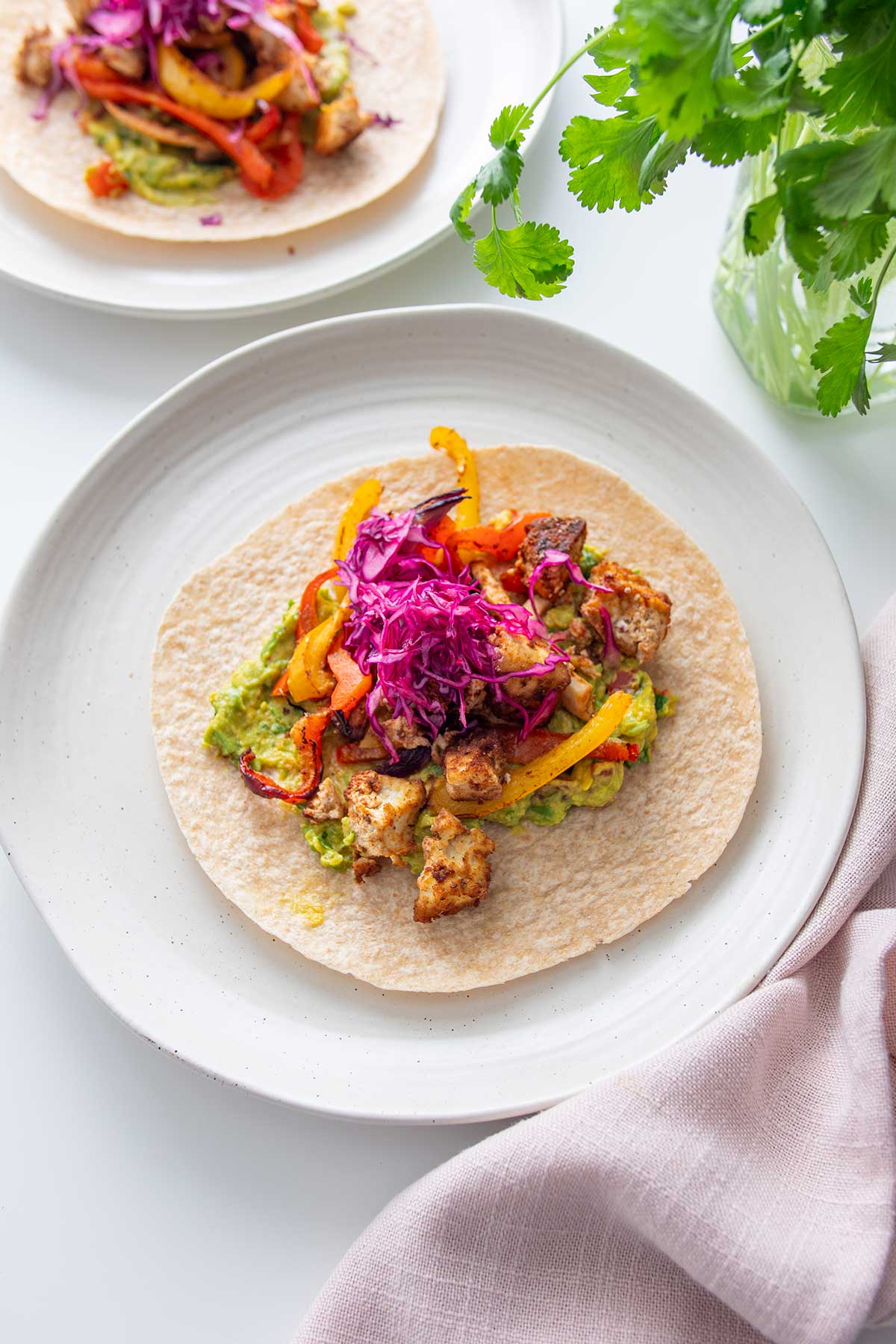 A deliciously assembled vegan fajita on a plate, highlighting the combination of tofu, vegetables, and vibrant purple cabbage.