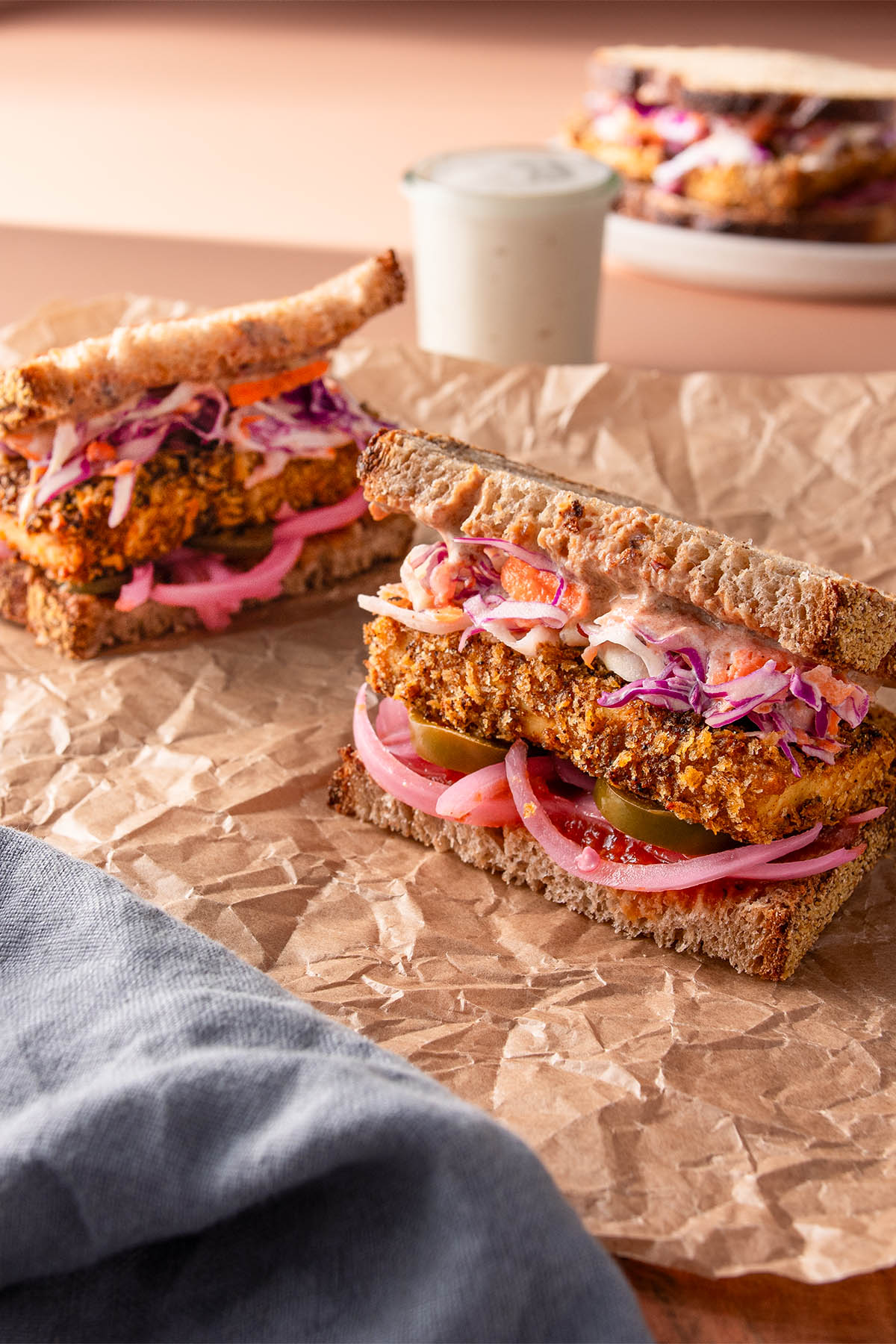 A vibrant sandwich cut in half with crispy bakes tofu.
