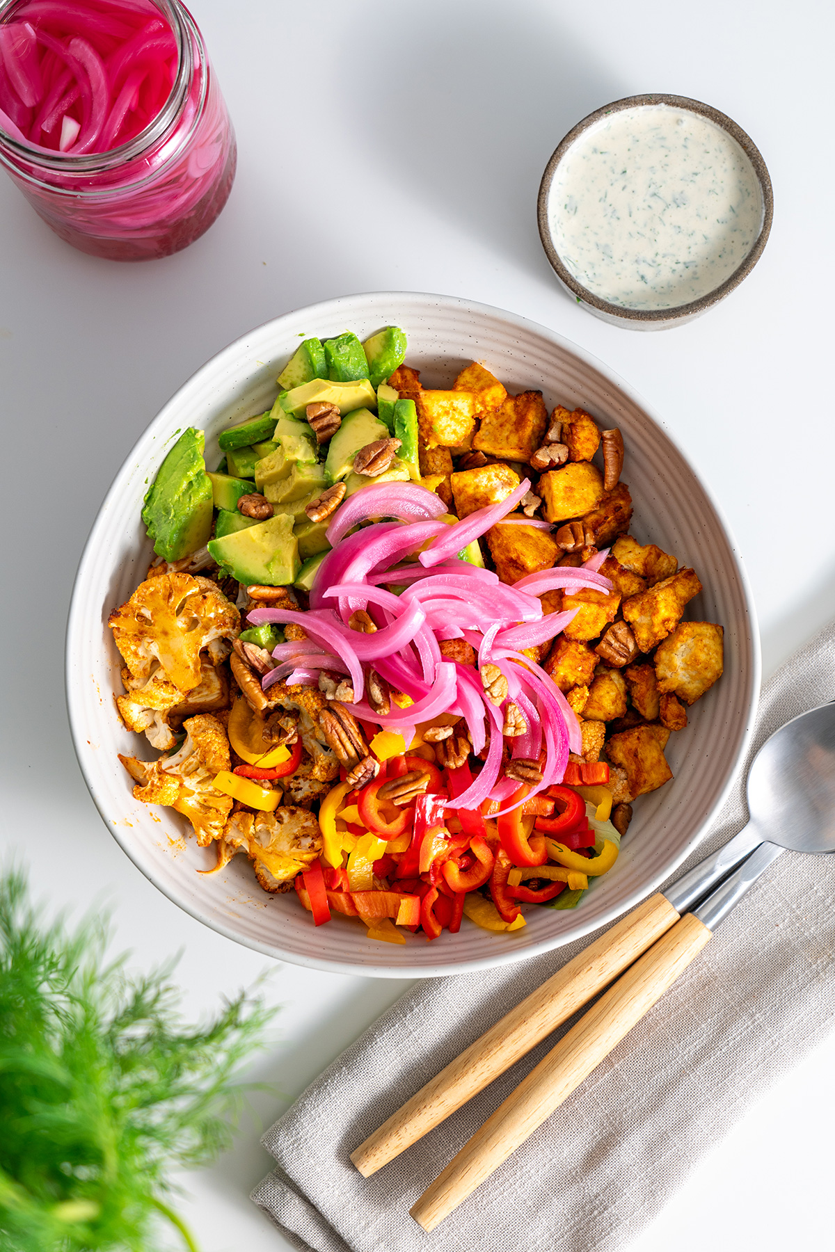 Overhead shot of a fresh, vibrant buffalo cauliflower salad with creamy ranch dressing on the side.