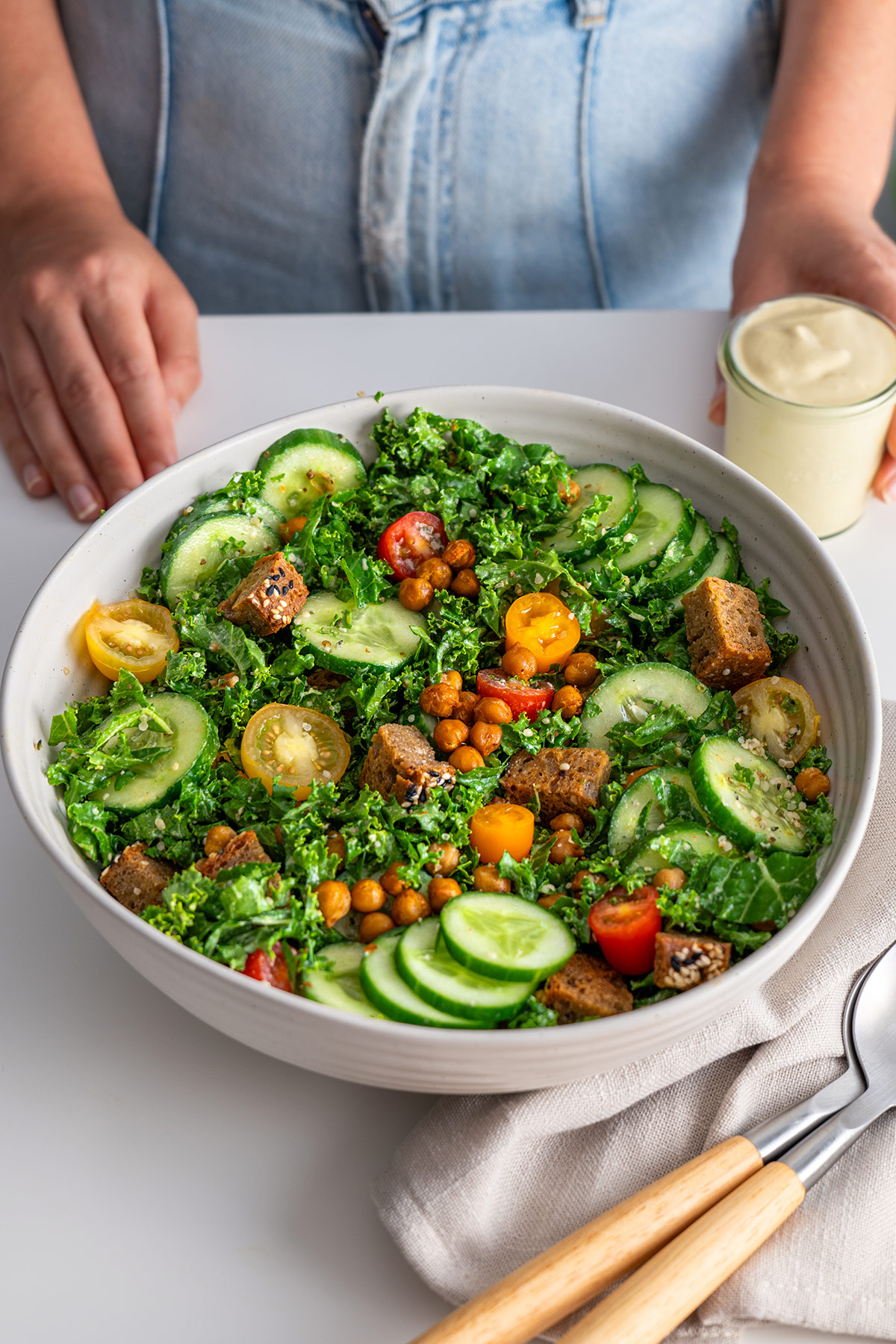 Finished High-Protein Kale Caesar Salad in a white bowl on a kitchen table.