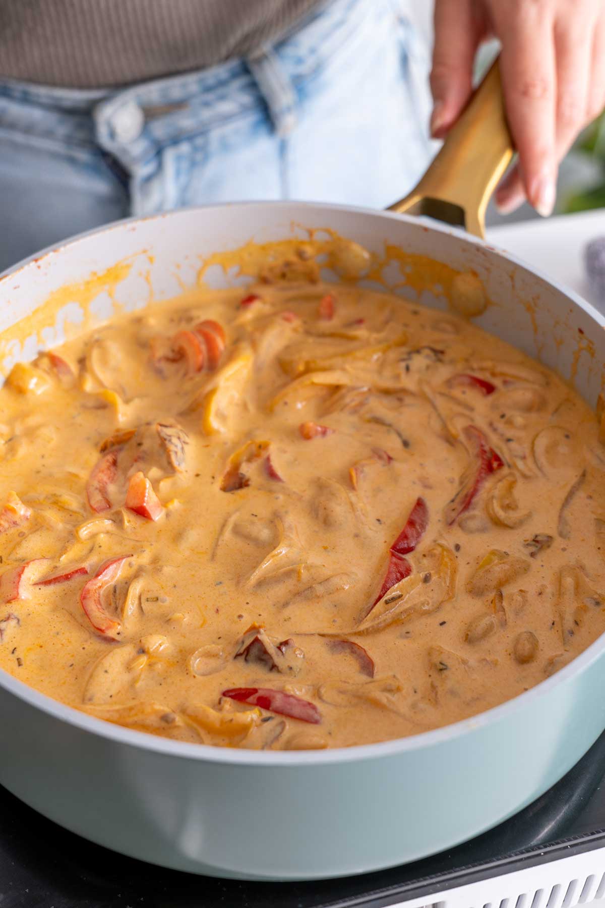 Golden cashew sauce poured over veggies in preparation for 'High-Protein Vegan Marry Me Pasta