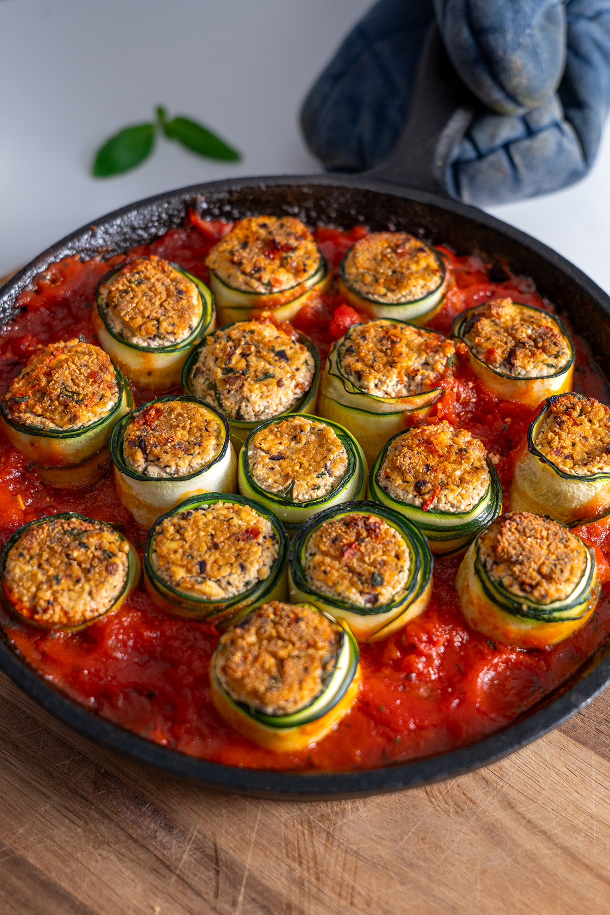 Detailed close-up of Mediterranean zucchini roll-ups in a skillet, highlighting the textured fillings and rolled zucchini.