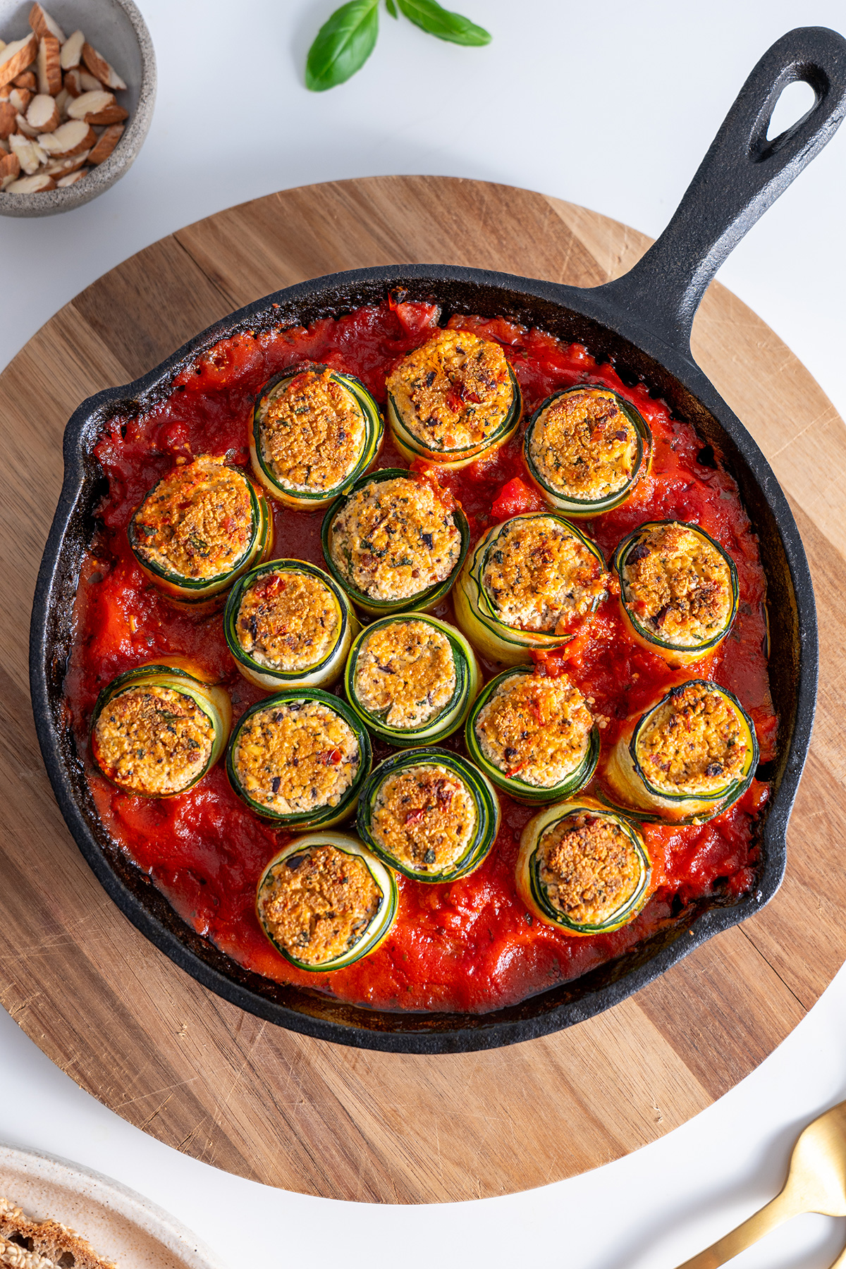 Close-up of Mediterranean zucchini roll-ups in a skillet, showcasing the crispy tops and vibrant tomato sauce.