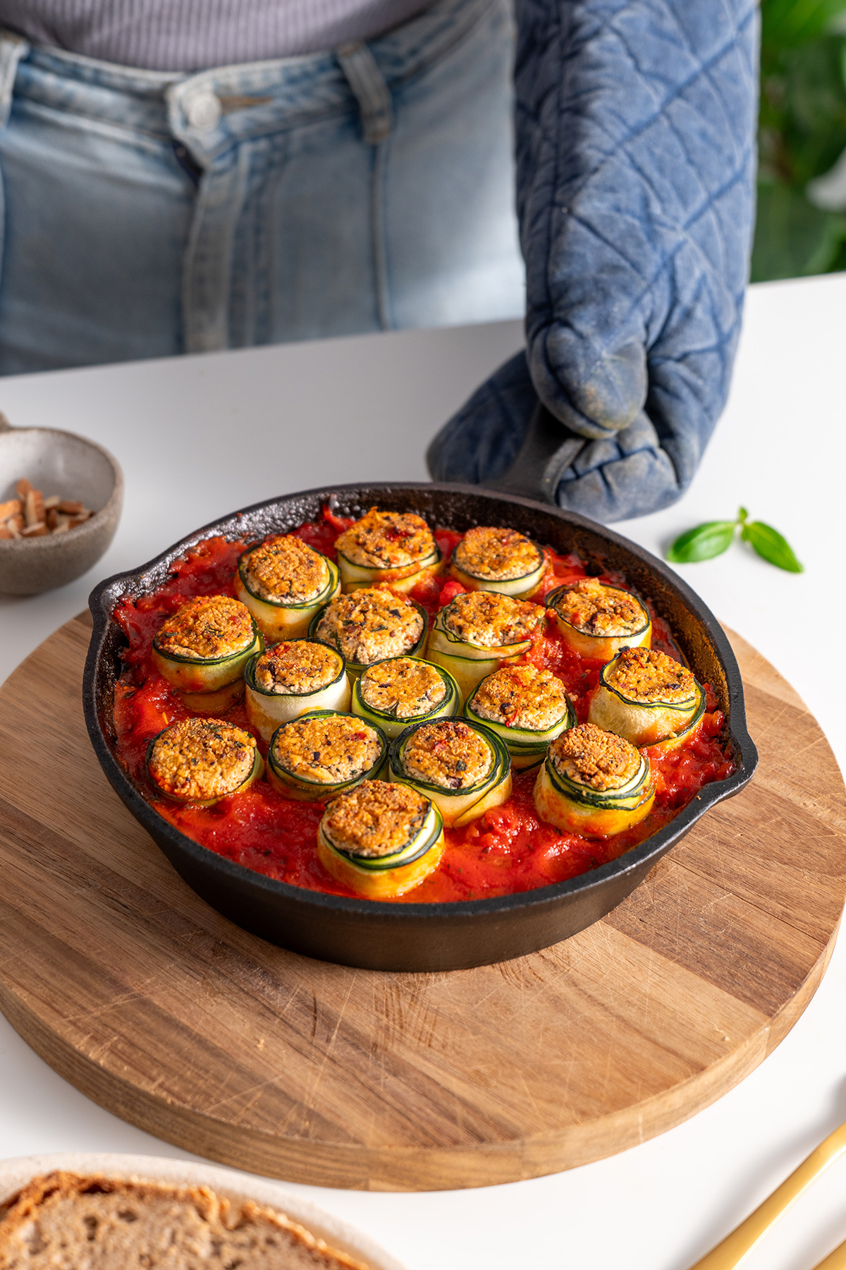 Freshly baked Mediterranean zucchini roll-ups served in a skillet on a wooden cutting board, ready to serve.