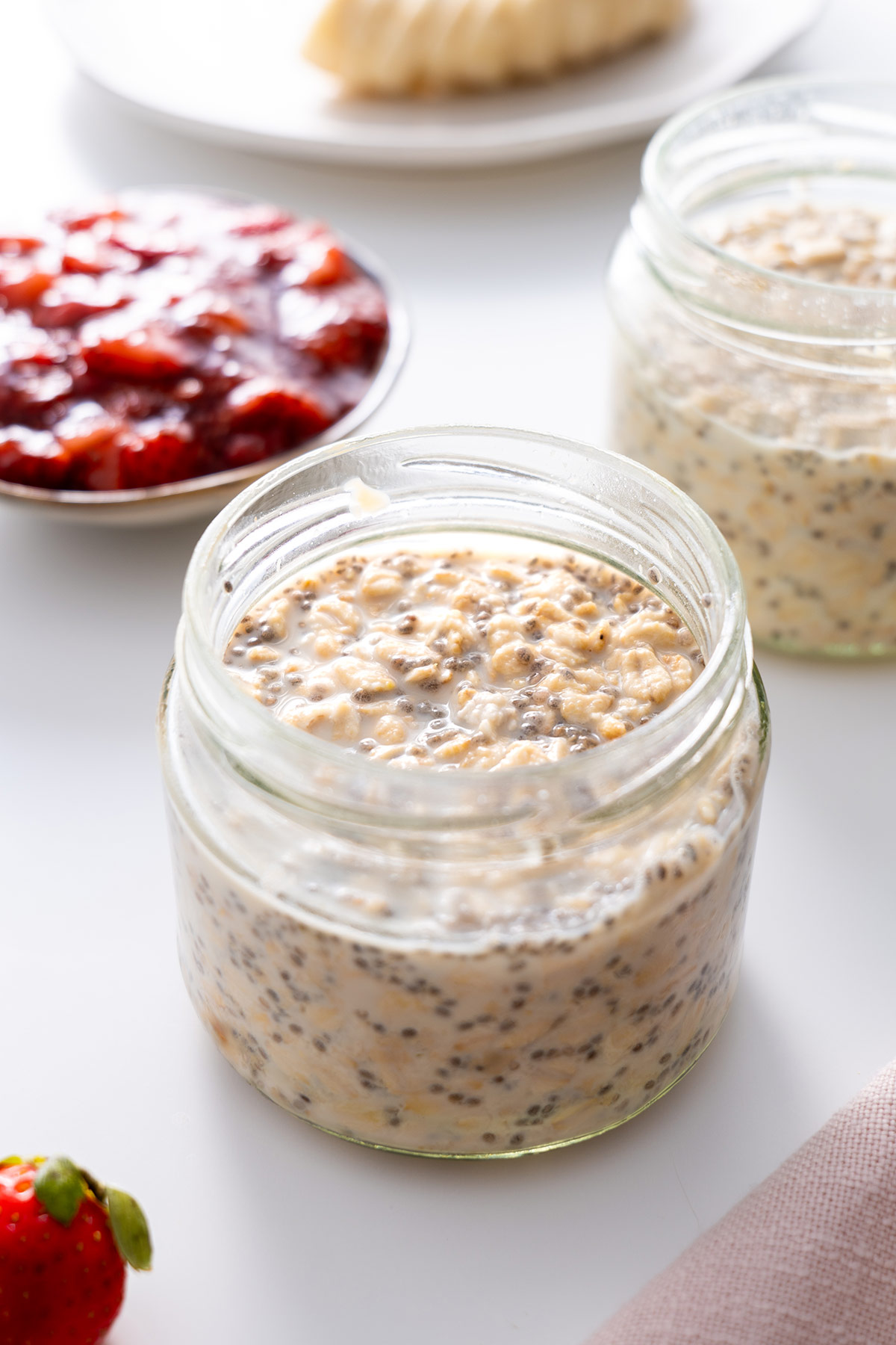 Peanut Butter and Jam Overnight oats in a clear glass jar, ready for toppings.