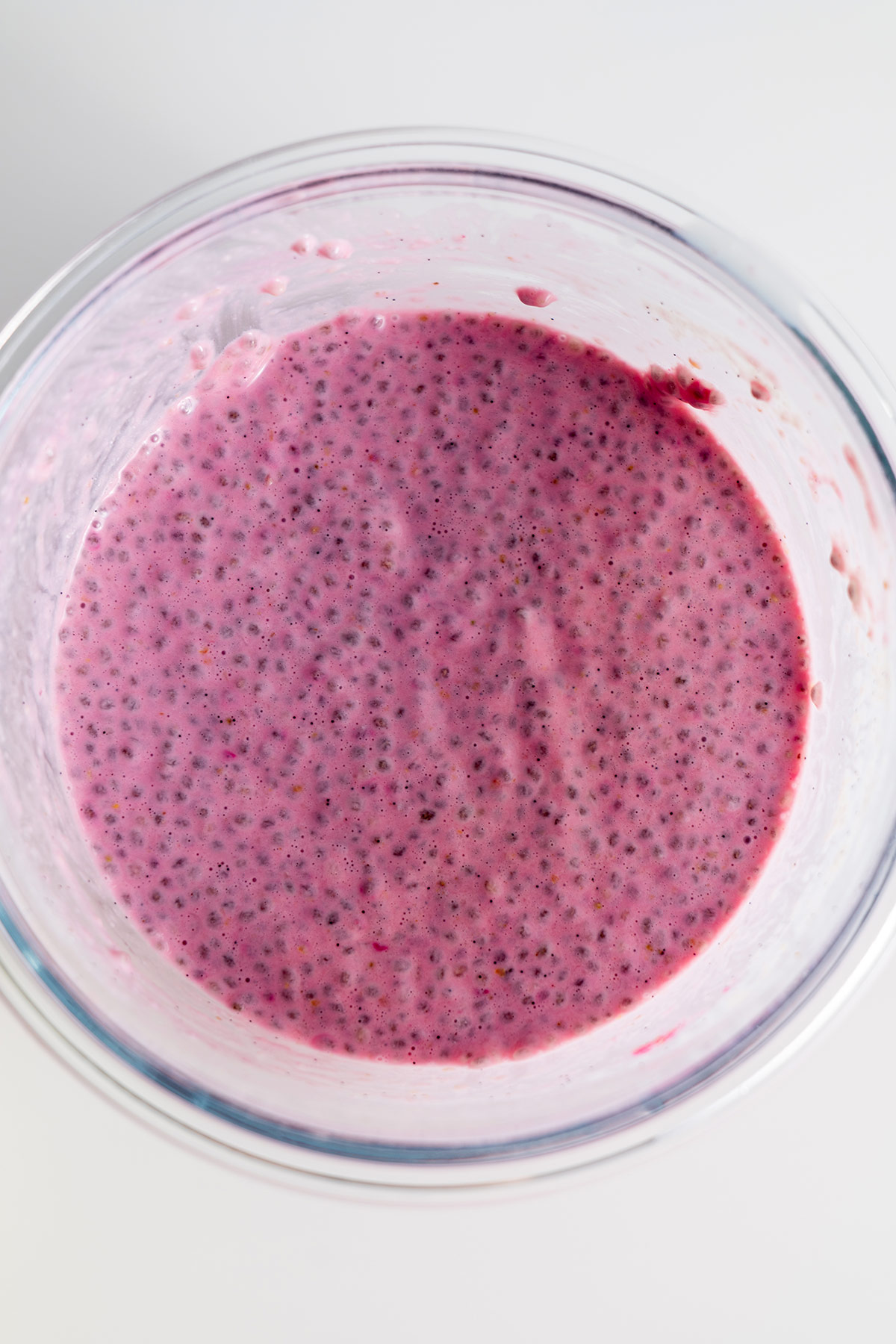 Top view of strawberry chia pudding mix in a glass bowl.
