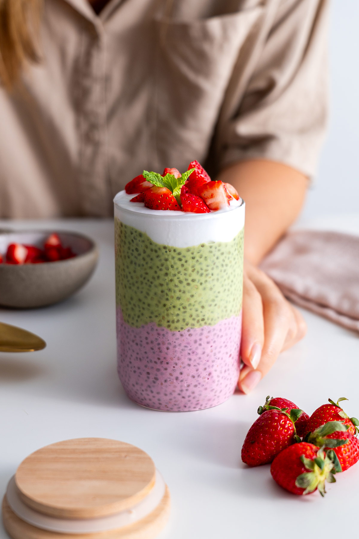 Hand holding a jar of strawberry matcha chia pudding.