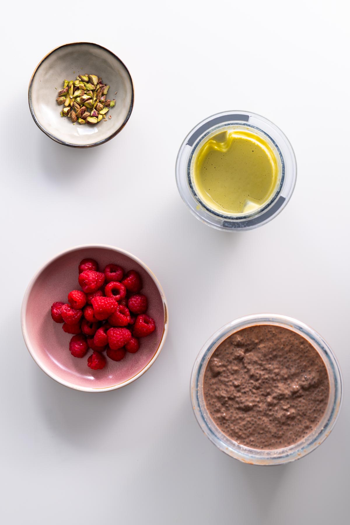 Ingredients laid out for Chocolate Pistachio Chia Pudding on a white surface.
