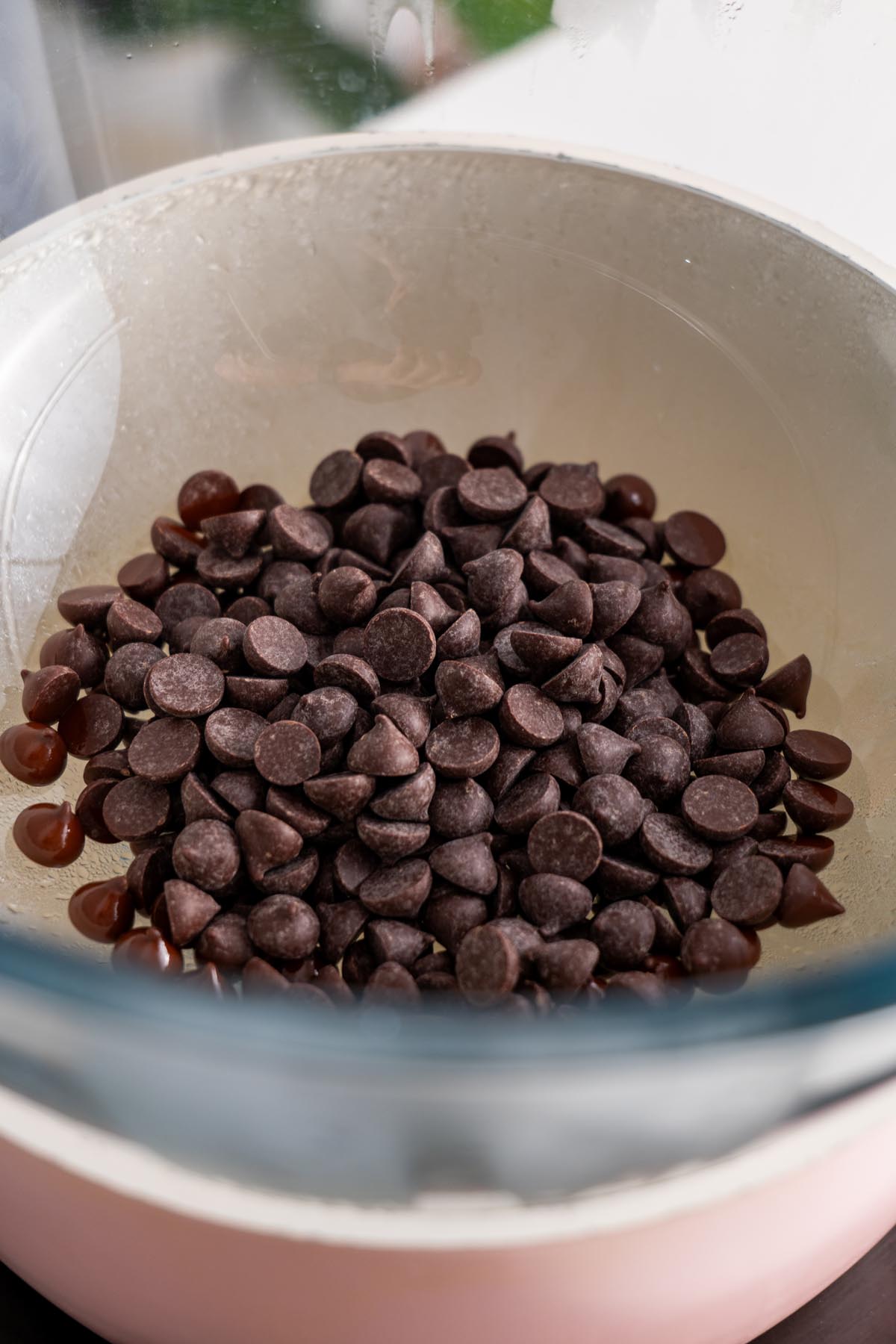 Close-up of dark chocolate chips in a glass bowl, ready to be melted.