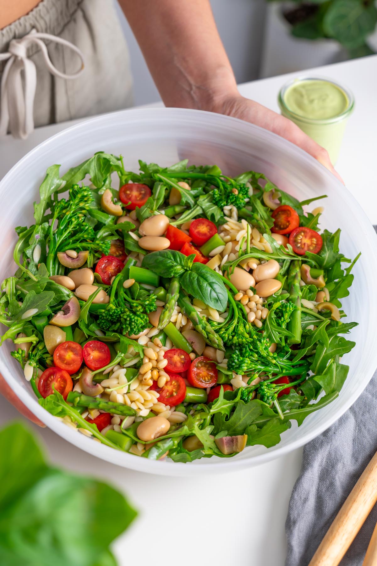 Close-up of a Pesto Orzo Salad in a white bowl ready to add salad dressing.