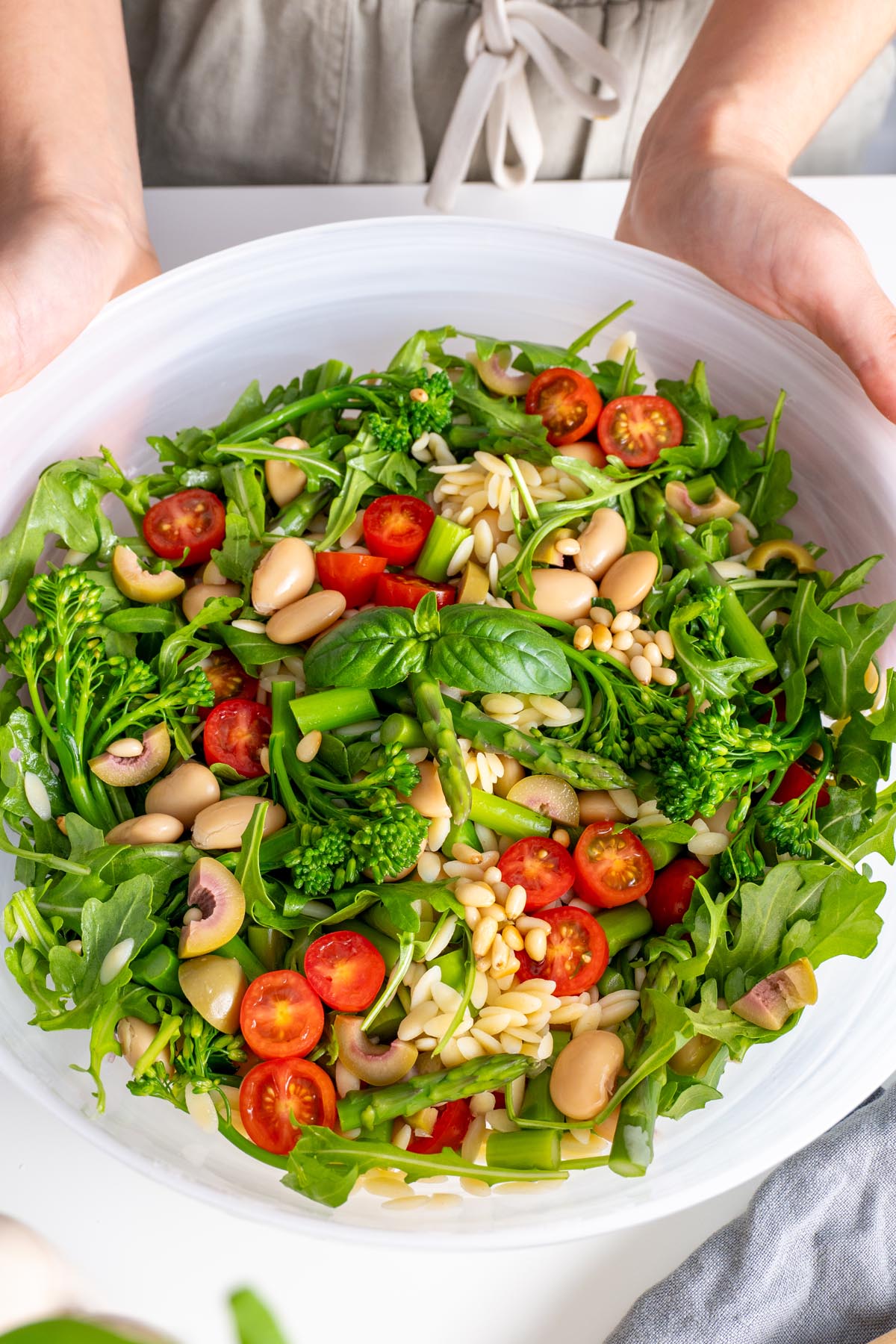 Detailed top view of a bowl of Pesto Orzo Salad, emphasizing the textures and vibrant colors of the fresh ingredients.