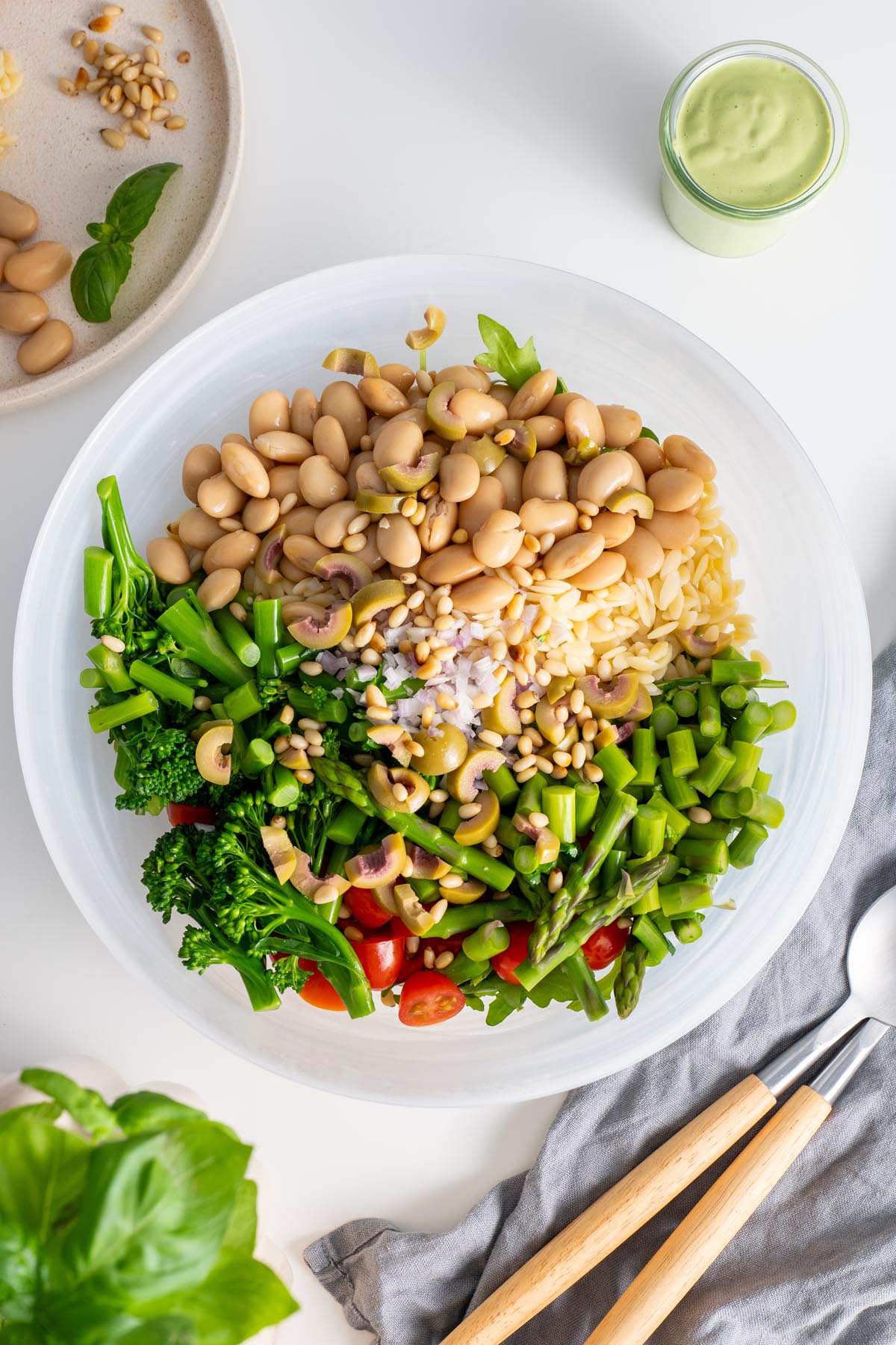 Detailed top view of a bowl of Pesto Orzo Salad, emphasizing the textures and vibrant colors of the fresh ingredients, ready to be tossed.