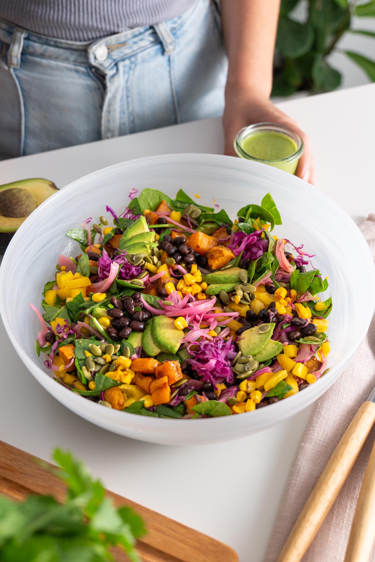Sarah assembling a colorful sweet potato salad in a white bowl.