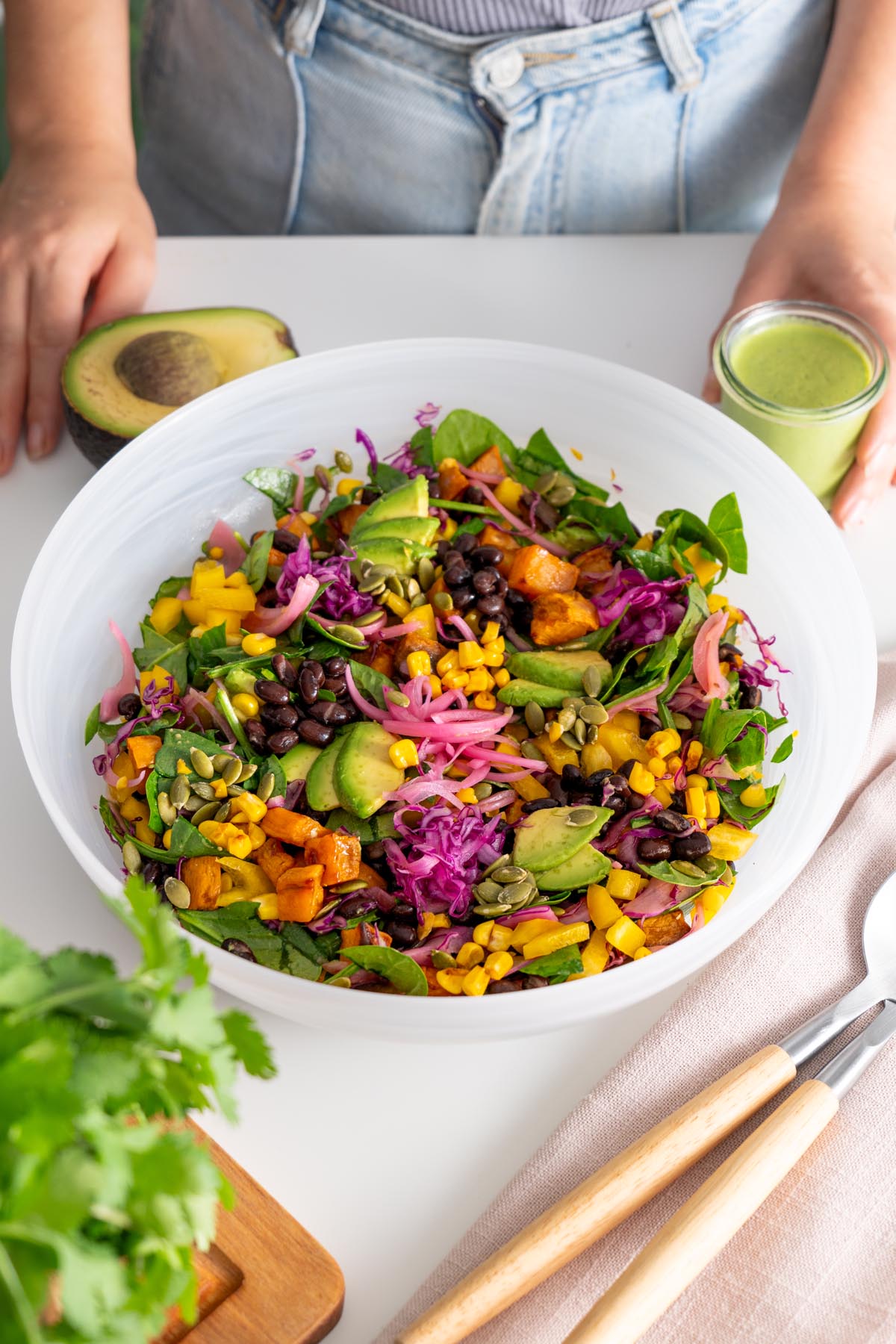 Close-up of a colorful sweet potato salad with creamy dressing in a white bowl.