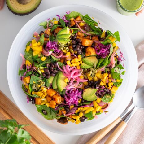 Overview of a colorful sweet potato salad served in a large white bowl on a white table.