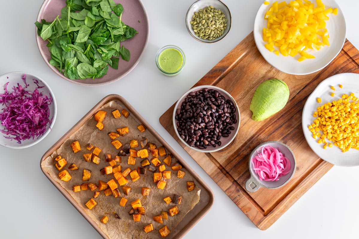 Ingredients prepared for a sweet potato salad arranged on a white table ready to be added to a salad bowl.