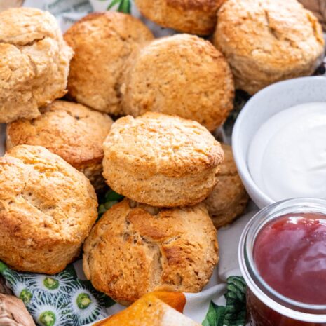 Vegan scones served in a rustic basket with condiments and a white napkin.