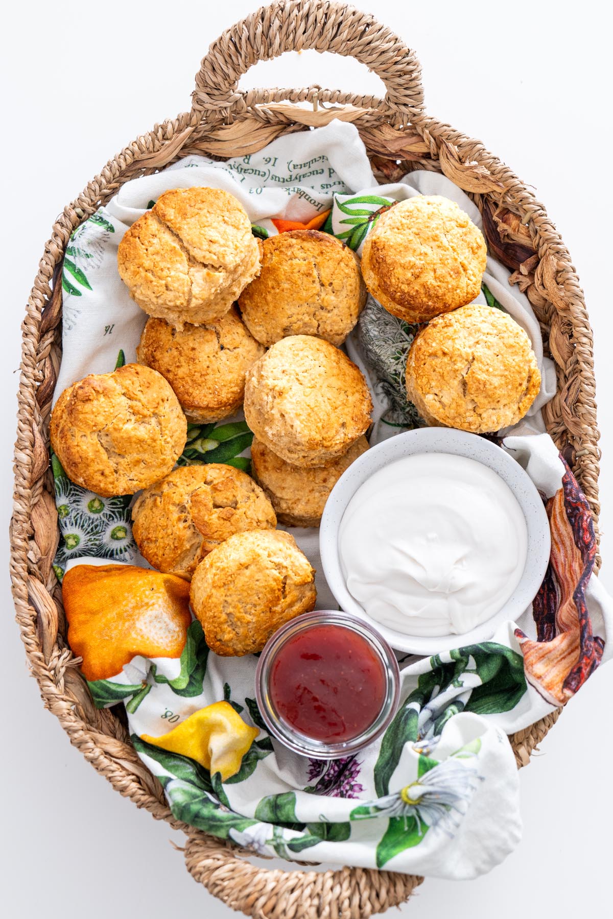 A picturesque basket filled with vegan scones, jam, and cream, ready for serving.