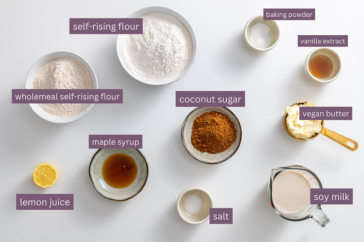 Assorted ingredients for vegan scones neatly arranged on a white surface.