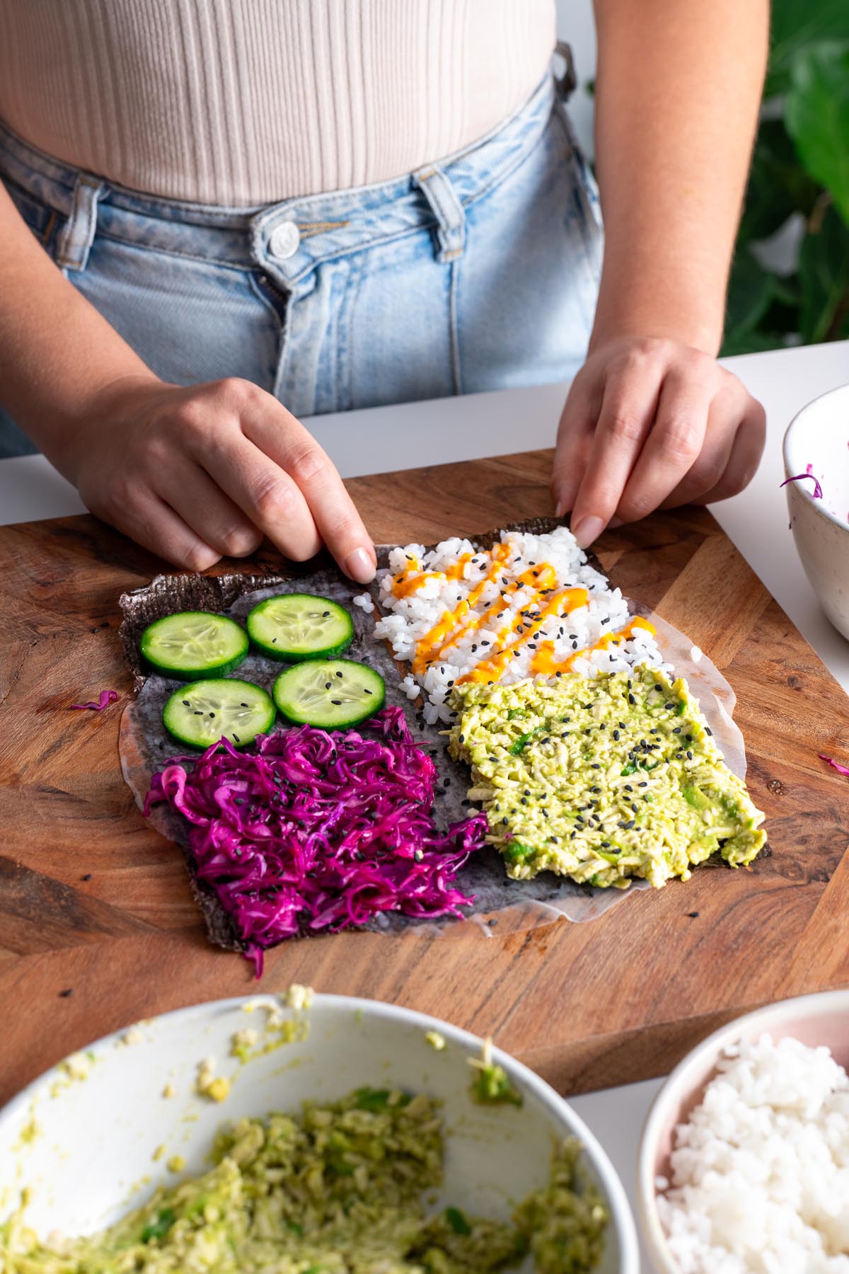 Hands folding a colorful veggie sushi wrap filled with fresh ingredients