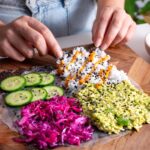 Hands folding a colorful veggie sushi wrap filled with fresh ingredients