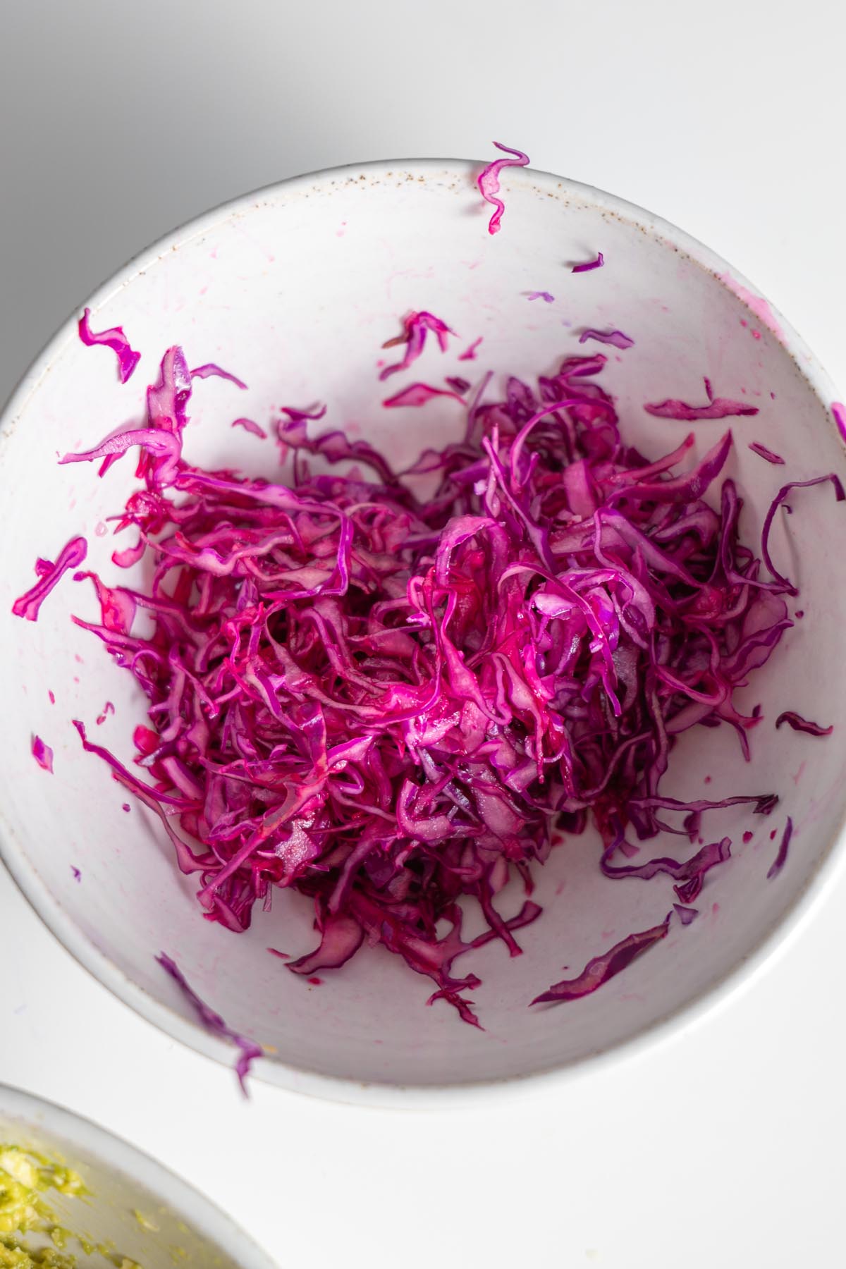 Bright red cabbage being mixed in a white bowl