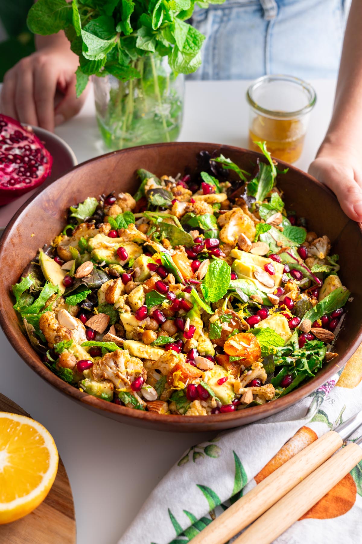 Close-up of spiced roasted cauliflower and chickpea salad in a wooden bowl with fresh ingredients.