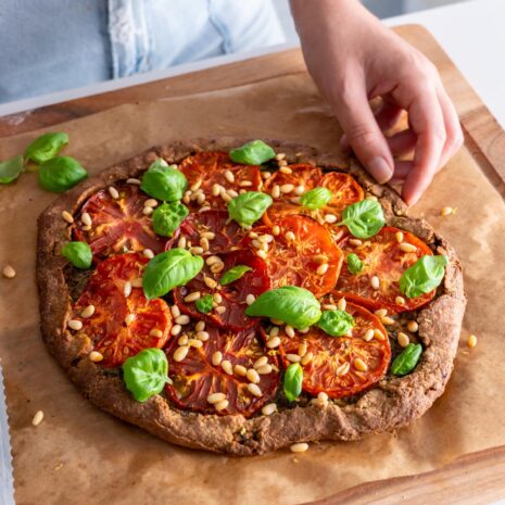 Finished Pesto Tomato Spelt Galette being garnished with fresh basil.