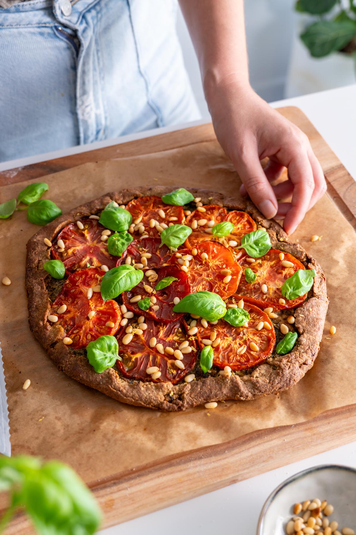 Finished Pesto Tomato Spelt Galette being garnished with fresh basil.