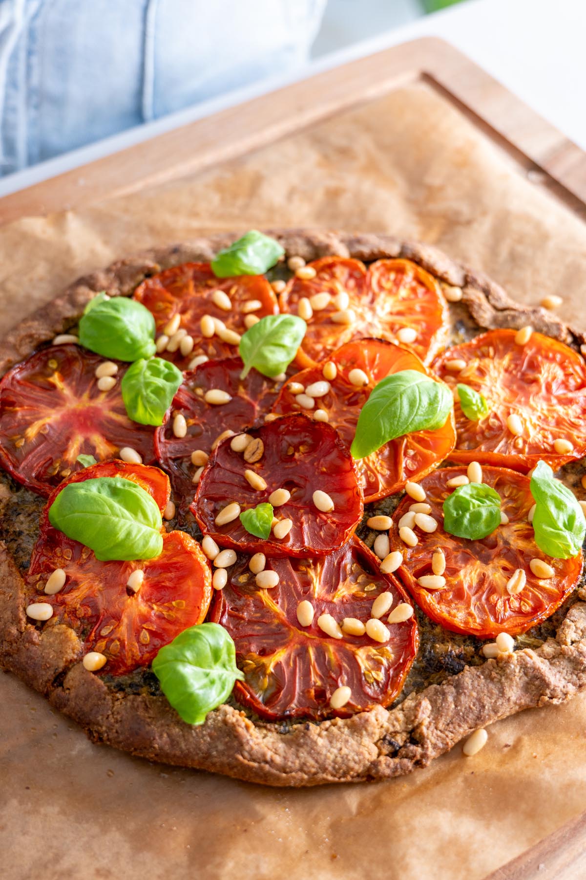 Close-up of a finished Pesto Tomato Spelt Galette garnished with pine nuts and fresh basil.