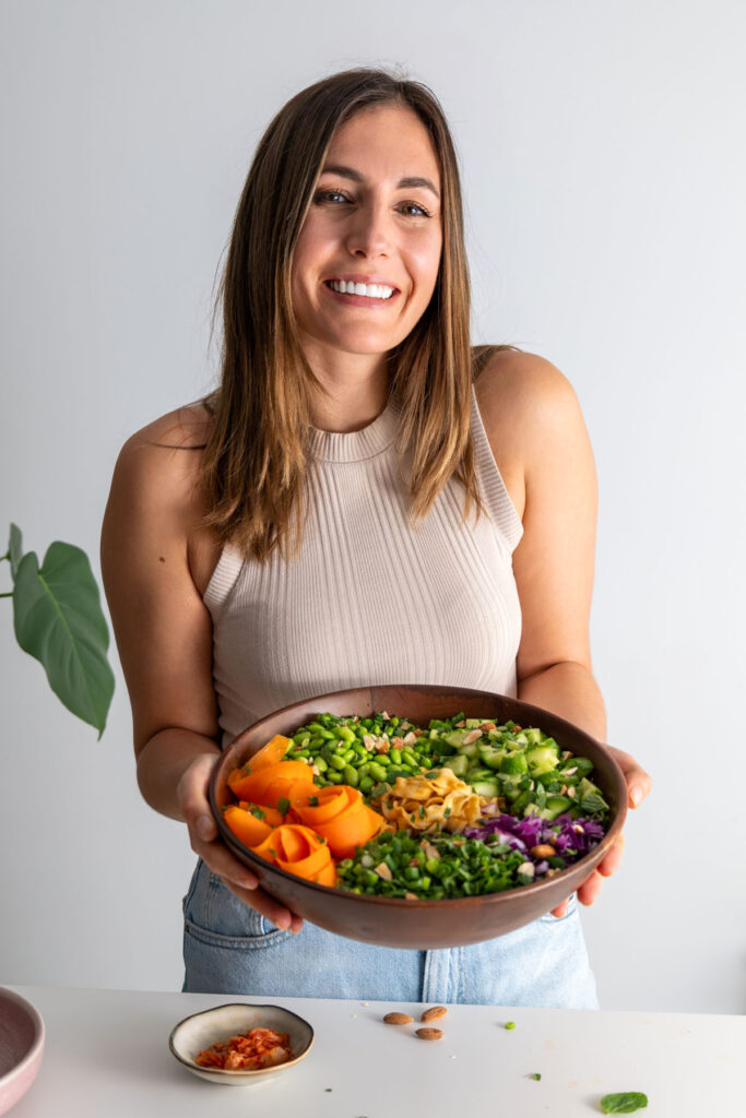 Sarah Cobacho, nutritionist holding a vibrant salad in a wooden bowl.
