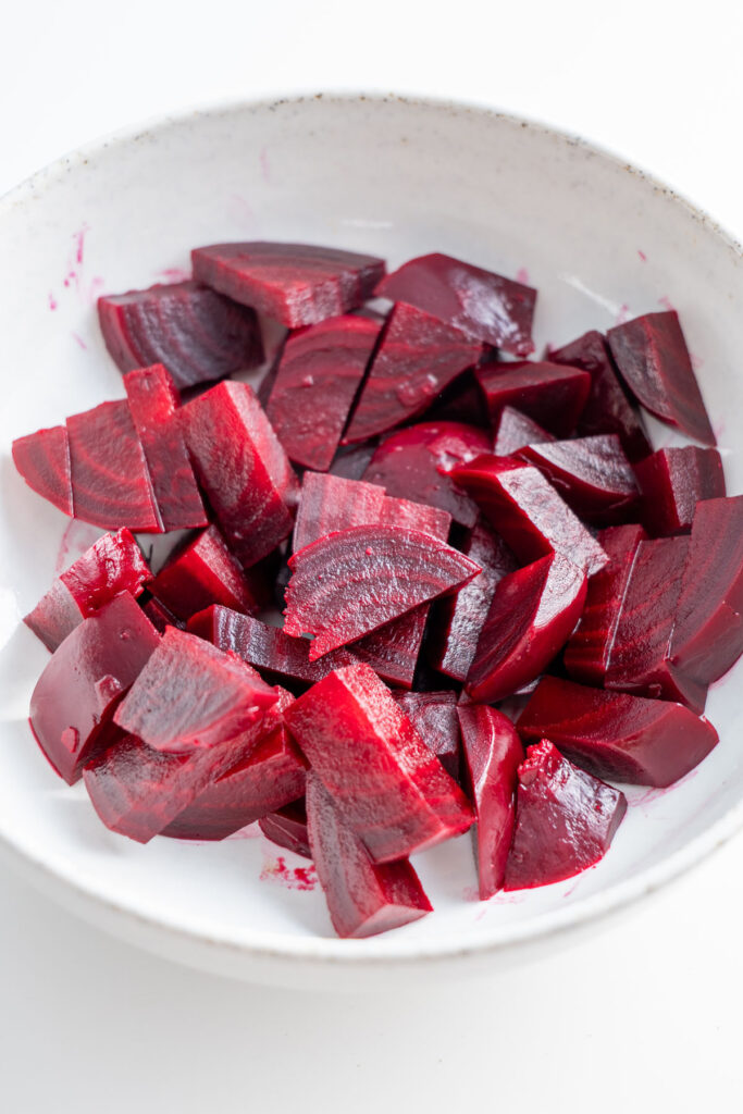 Close-up of chopped beetroot pieces in a white bowl.