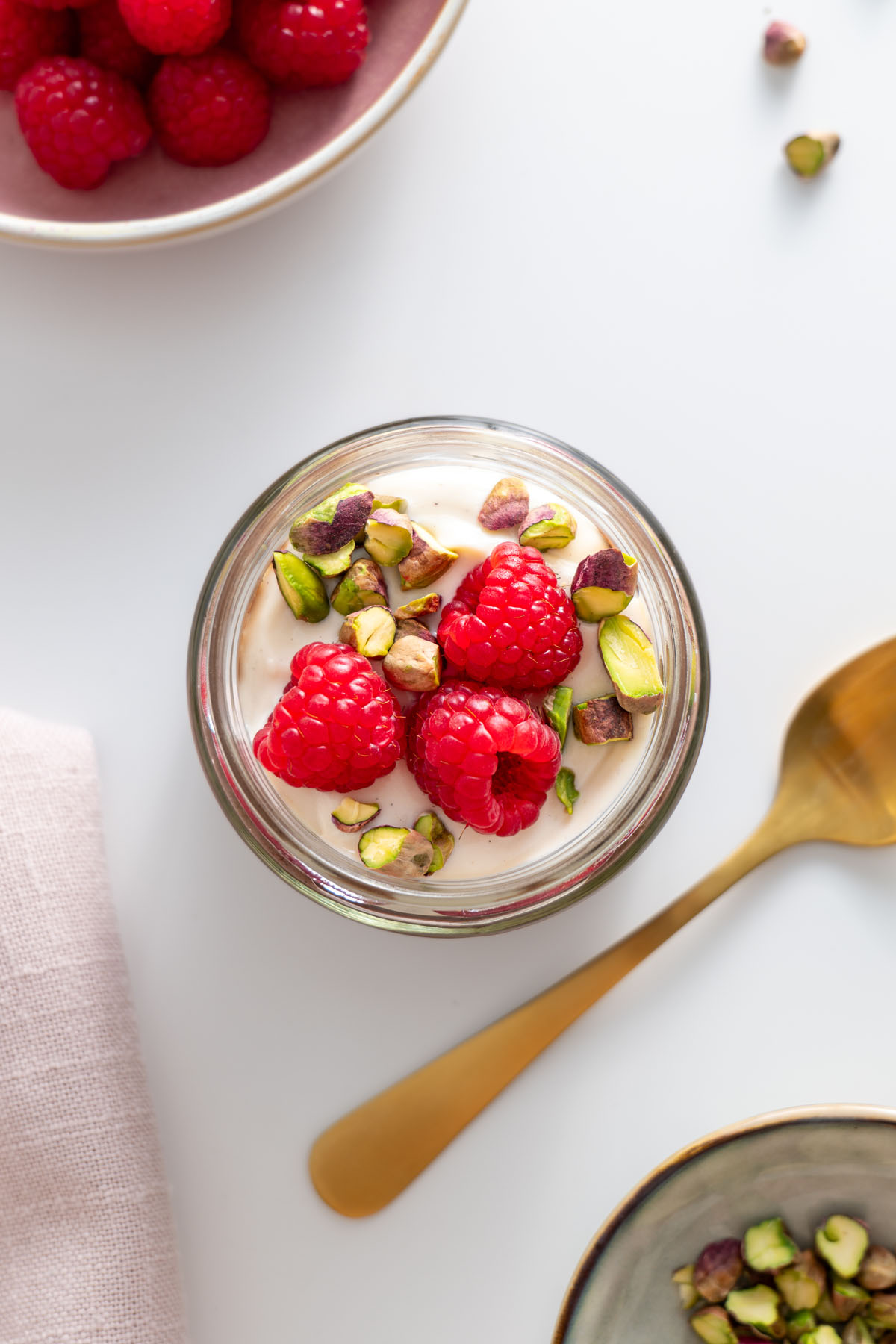 Overhead view of a jar of cacao chia pudding with fresh raspberries and pistachios.