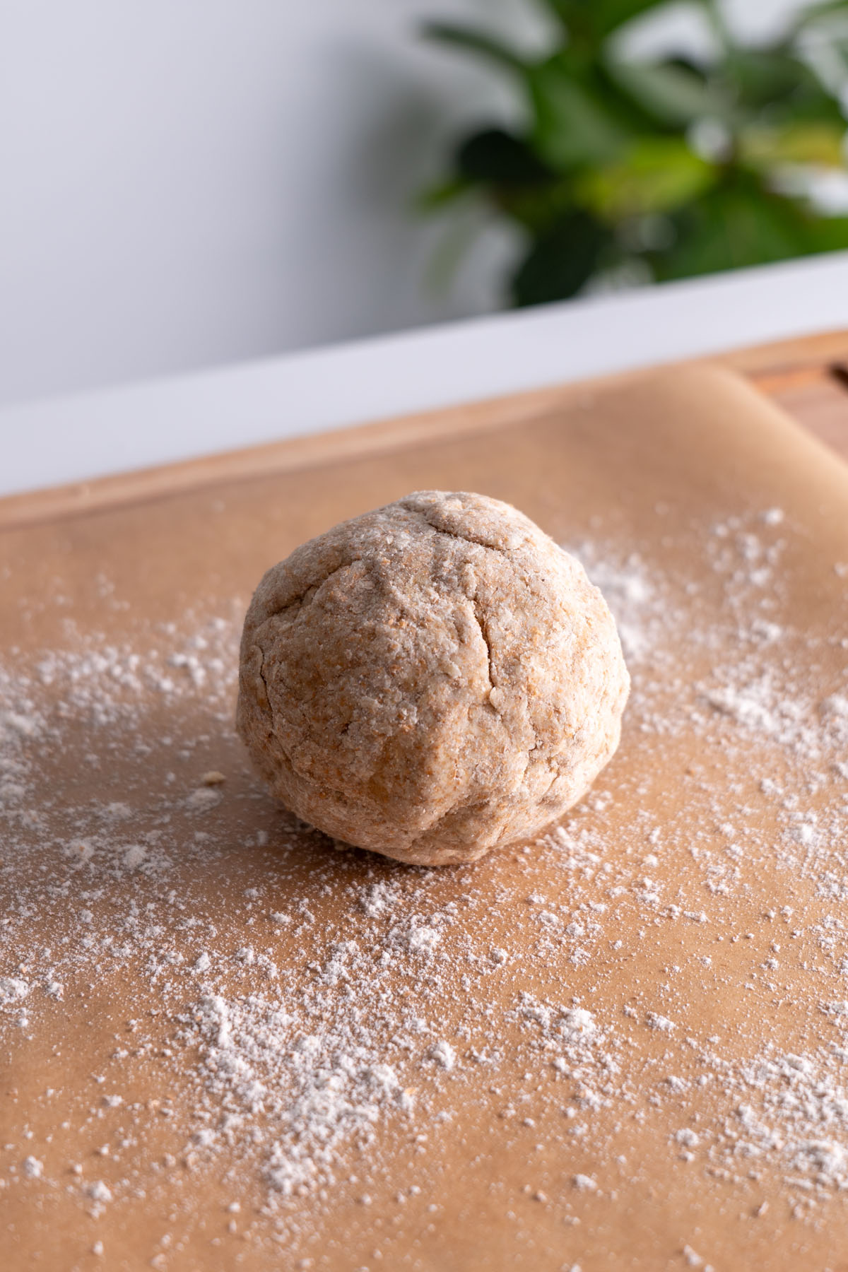 Wholemeal spelt flour dough ball on a floured parchment paper surface.