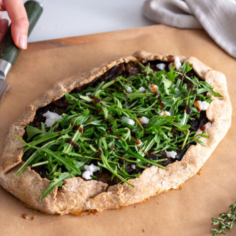 Galette topped with fresh arugula, plant-based feta, and balsamic glaze.