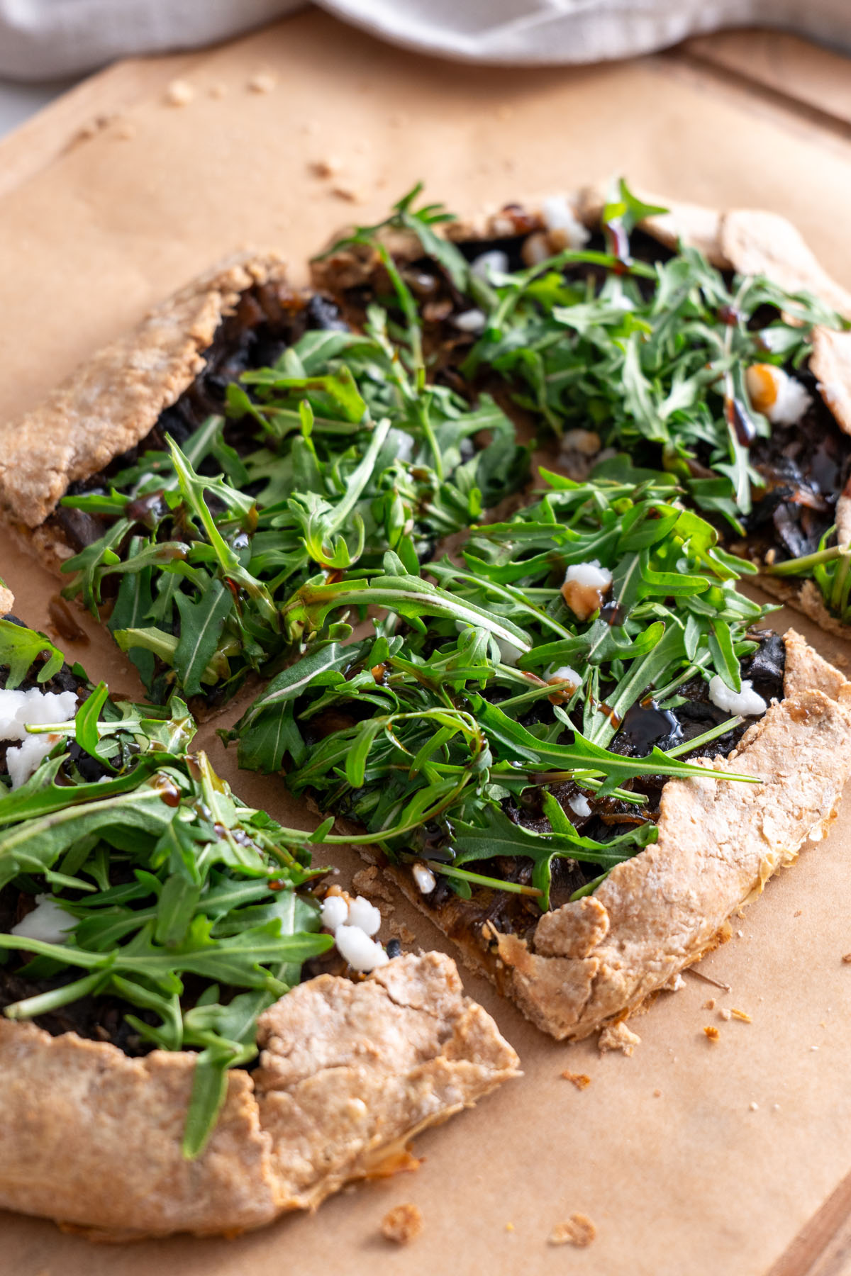 Sliced caramelized onion mushroom galette topped with fresh arugula.