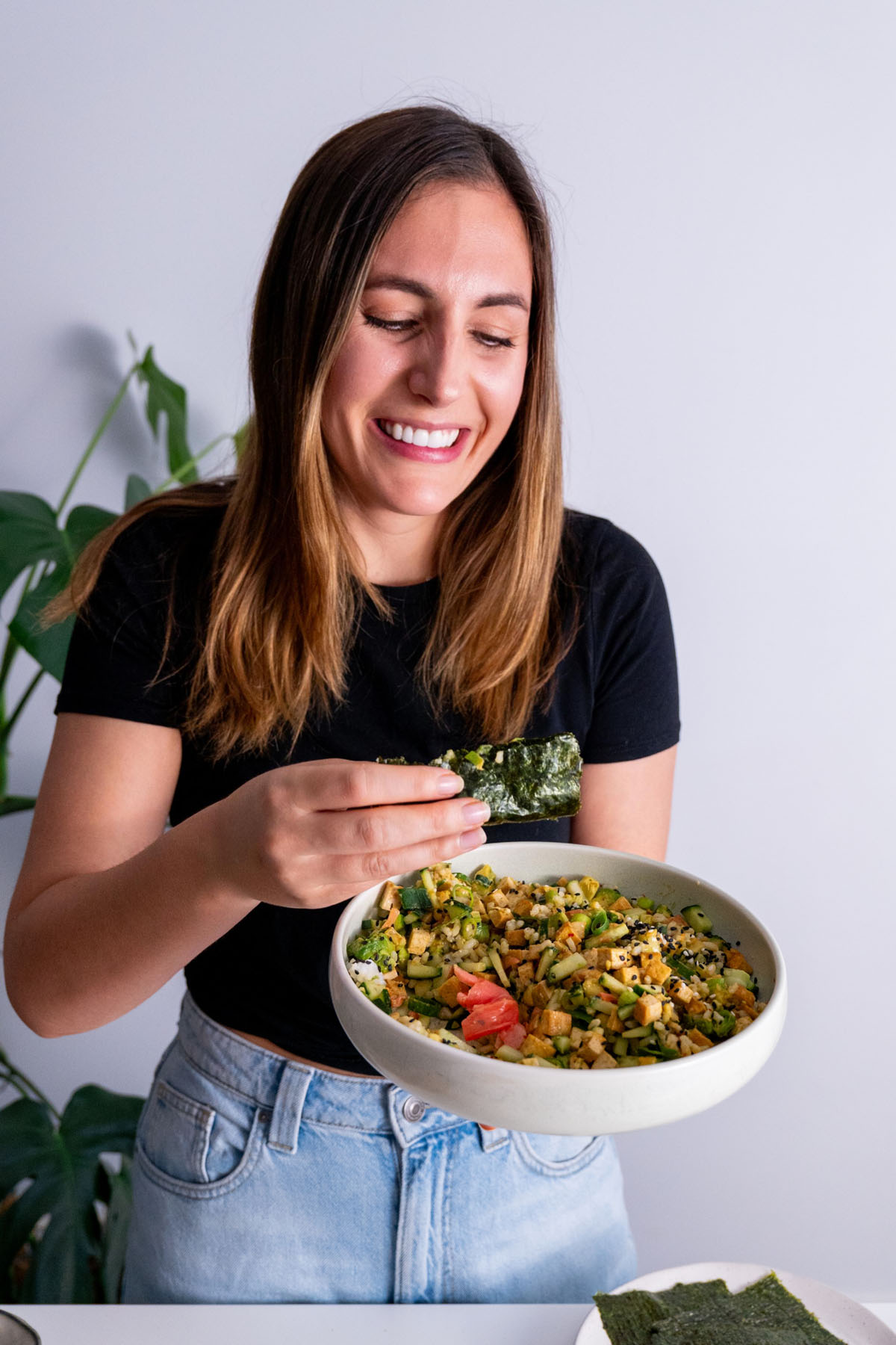 Sarah Cobacho smiling and holding a High-Protein Vegan Sushi Bowl.