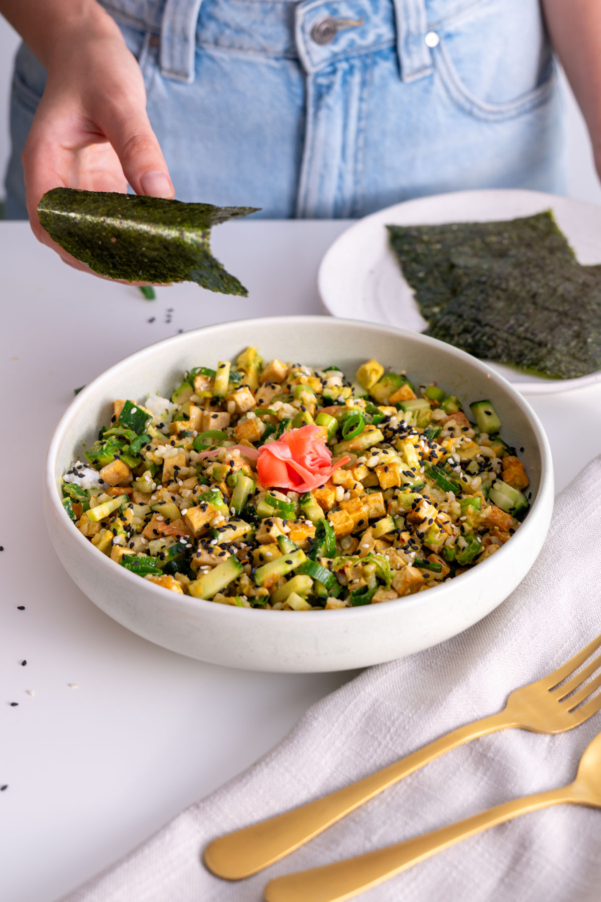 Sarah Cobacho holding a nori sheet above a sushi bowl.