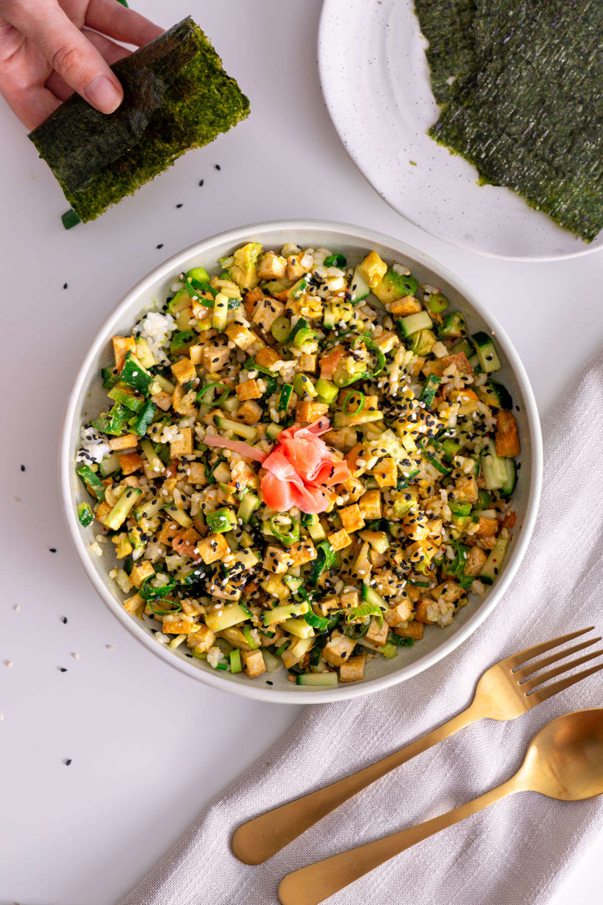 Close-up of High-Protein Vegan Sushi Bowl with nori sheet in hand.