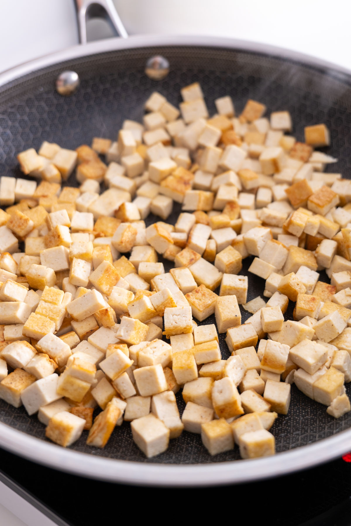 Tofu cubes cooking in a frying pan.