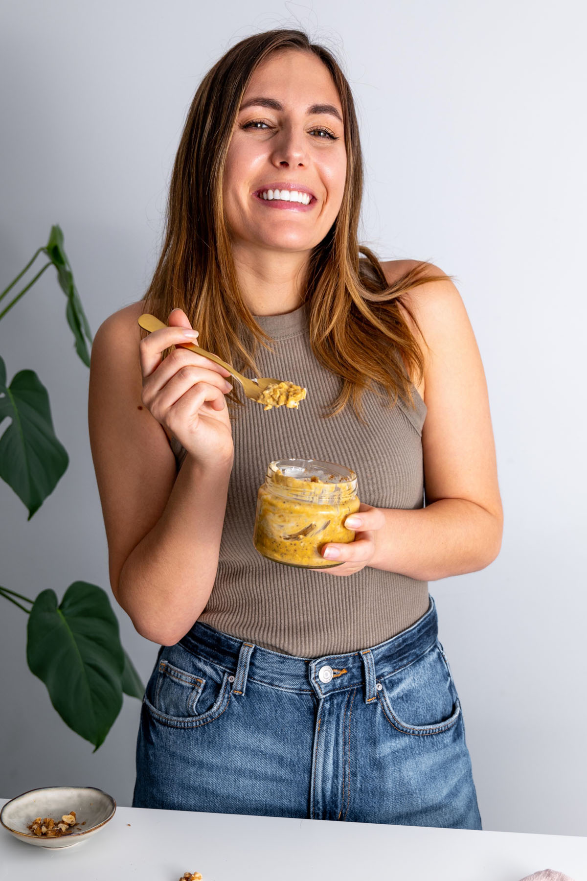 Sarah Cobacho smiling and holding a jar of pumpkin spice overnight oats