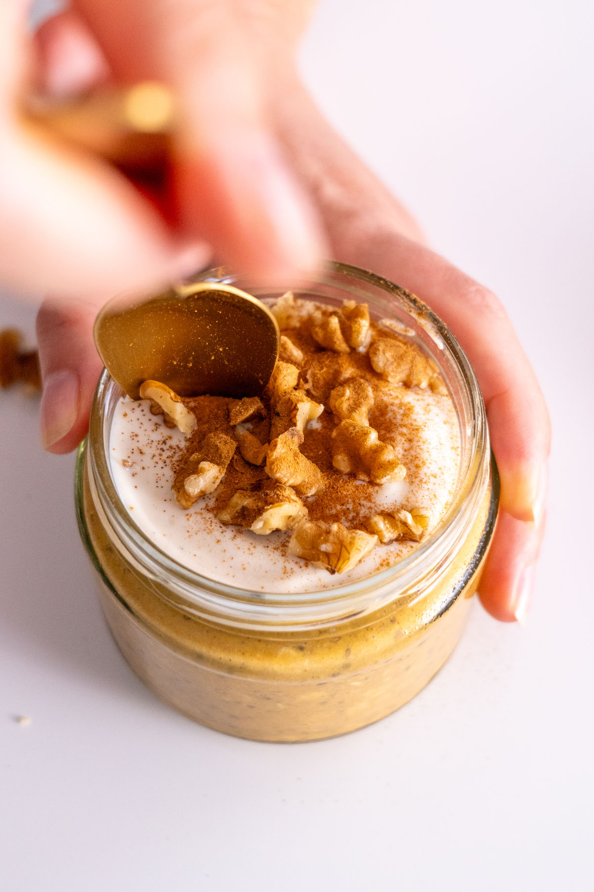 Close-up of Sarah Cobacho holding a spoon next to a jar of pumpkin spice overnight oats