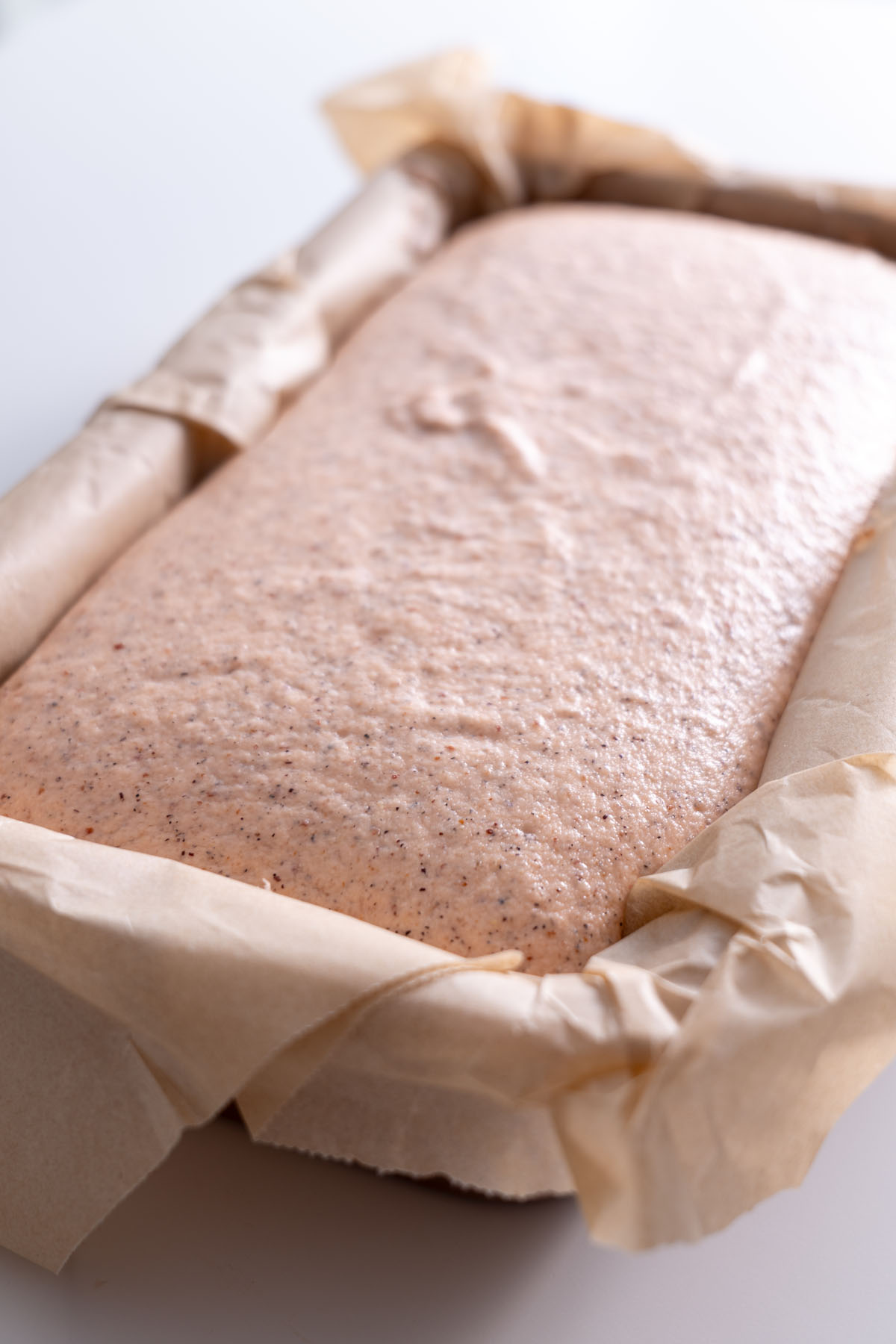 Red lentil quinoa bread batter in a parchment-lined loaf pan.