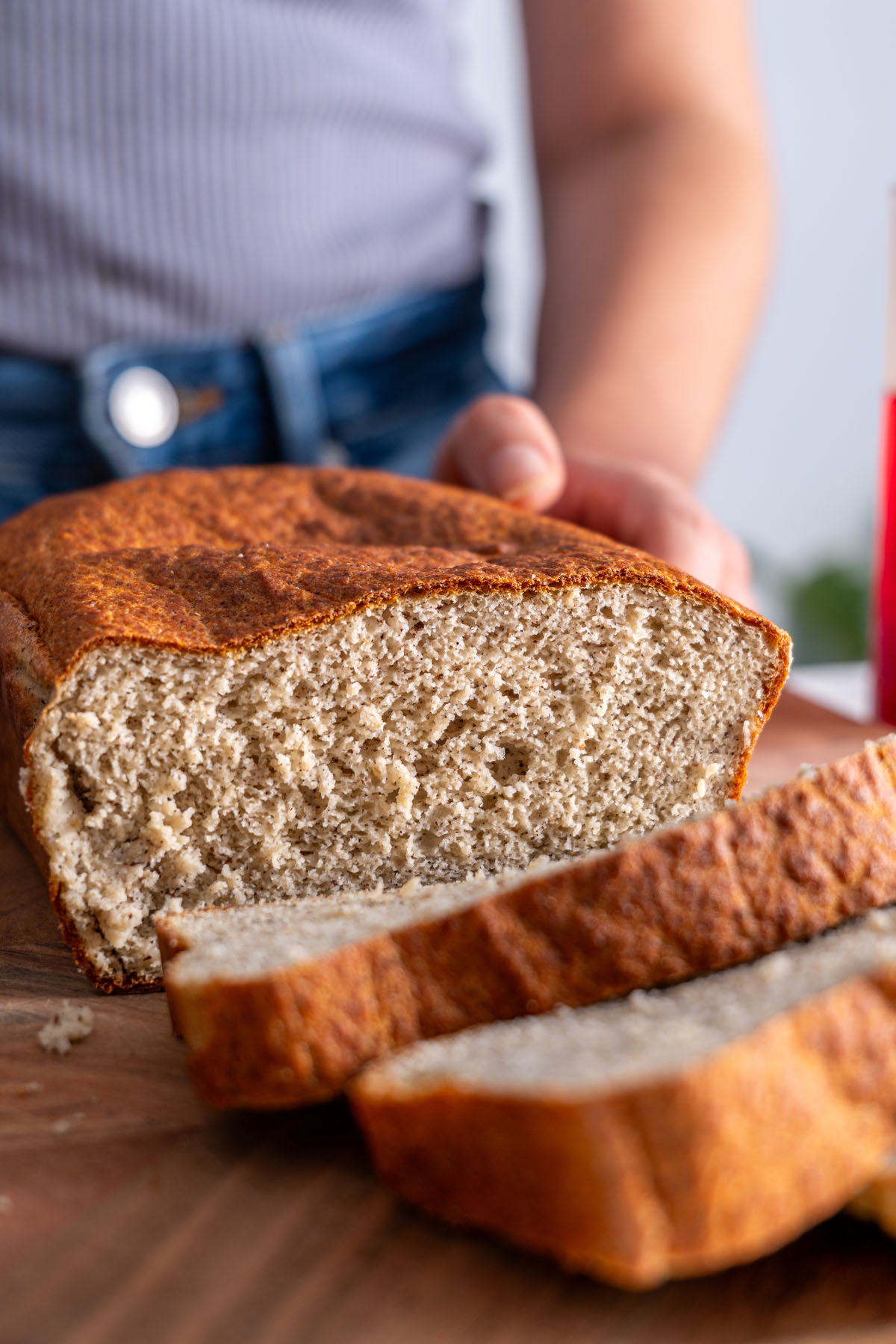 Freshly baked loaf of red lentil quinoa bread resting on a wooden board.