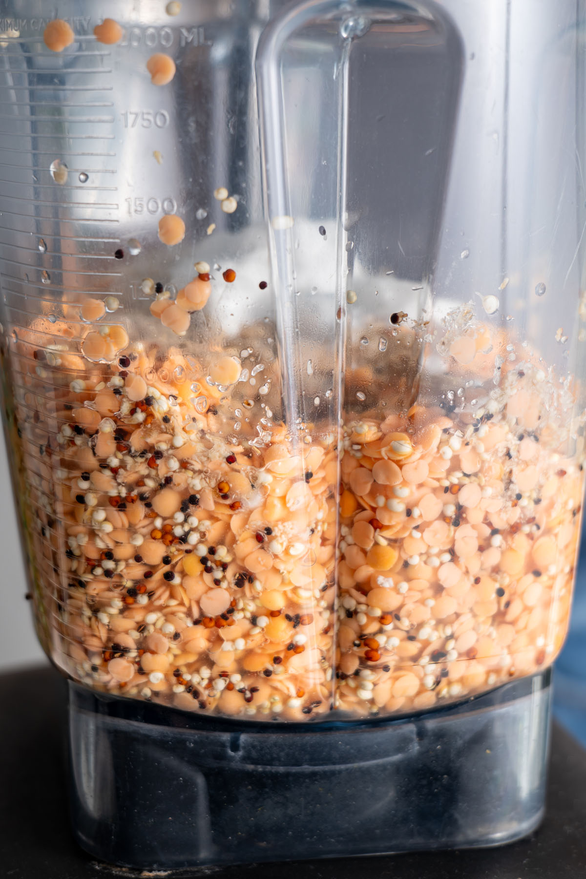 Split red lentils and quinoa soaking in water inside a blender.