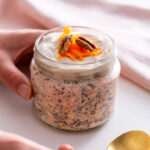 Sarah Cobacho holding a jar of carrot cake overnight oats with pecans and yogurt on top, ready to serve.